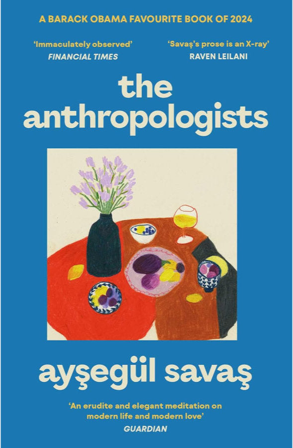 Book cover of 'The Anthropologists' by Aysegul Savas with a blue background and illustration of a table with flowers and a vase.