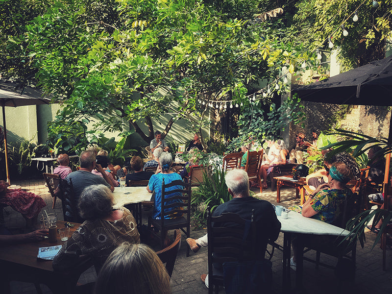 Guests listen to a speaker in the garden courtyard at Wild & the Sage bookshop in Galle