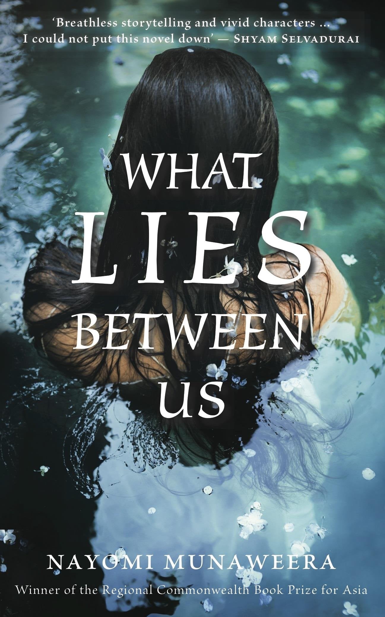 Book cover of What Lies Between Us by Nayomi Munaweera at Wild and the Sage, Galle, Sri Lanka